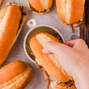 a french dip sandwich getting dipped into au jus