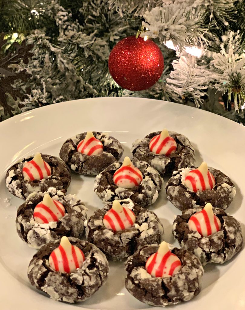chocolate cookies coated in powdered sugar and topped with a candy cane hershey kiss