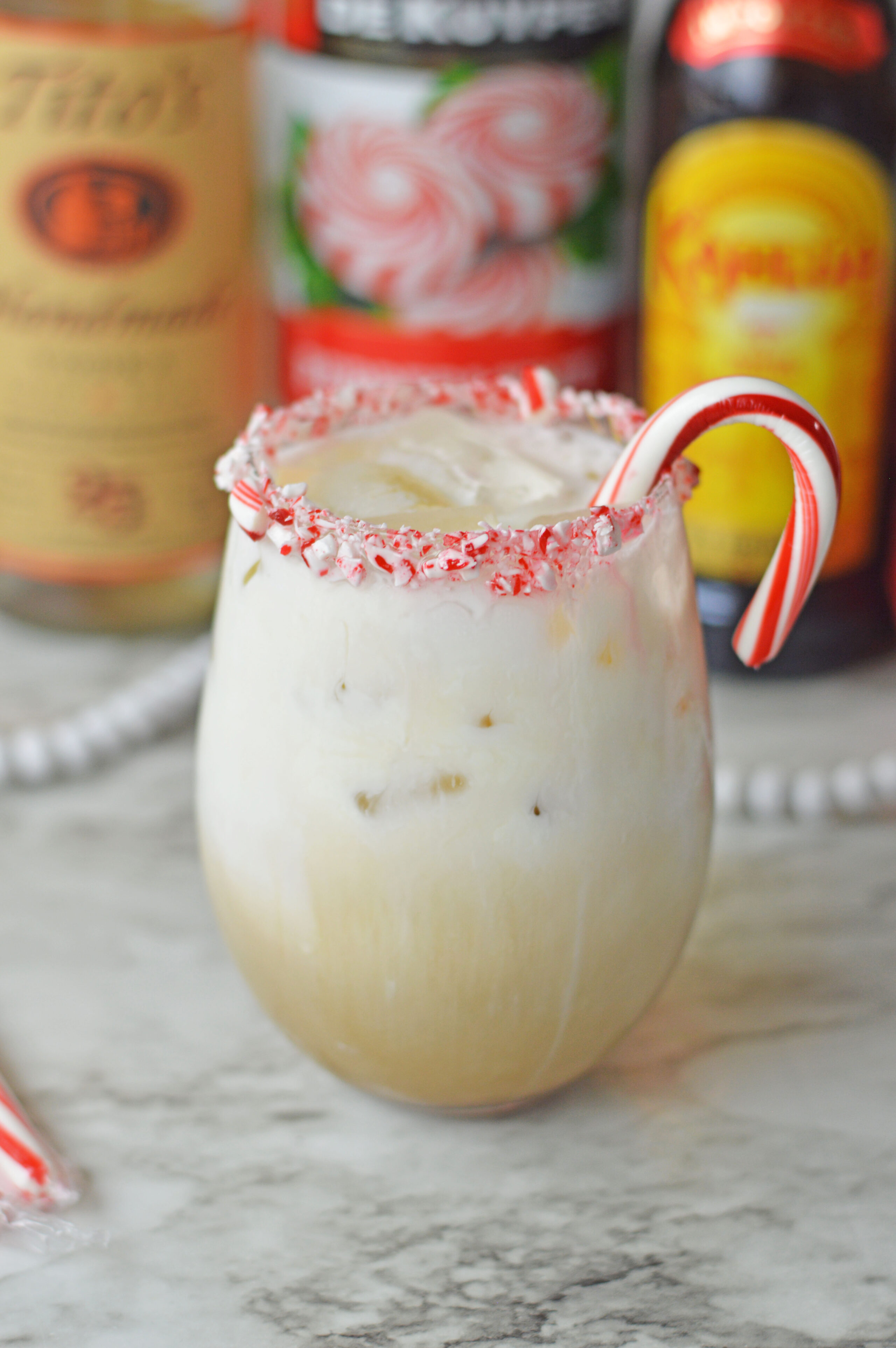 a creamy peppermint white Russian in a glass with a candy cane.