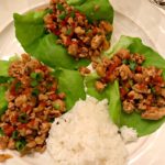 cooked, asian flavored chicken wrapped in a lettuce leaf as an appetizer or main meal
