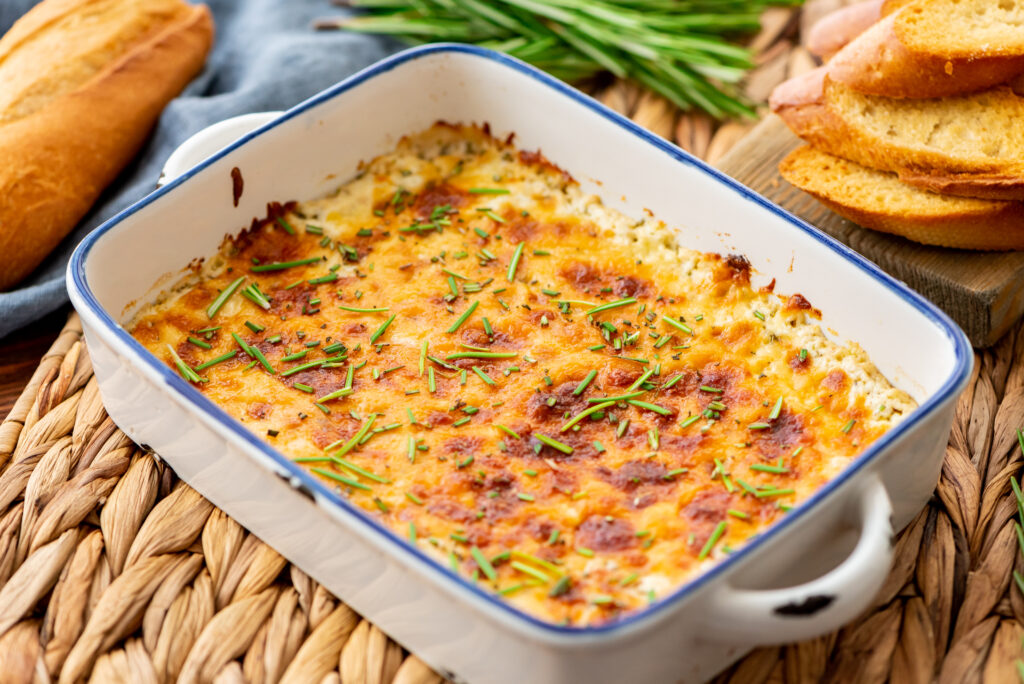a creamy cheese dip with garlic, herbs, and lemon in a baking dish.