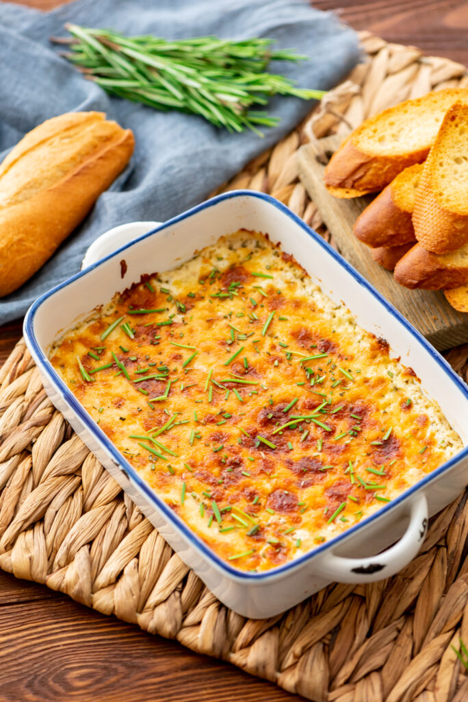 a creamy baked cheese dip with fresh herbs on top.