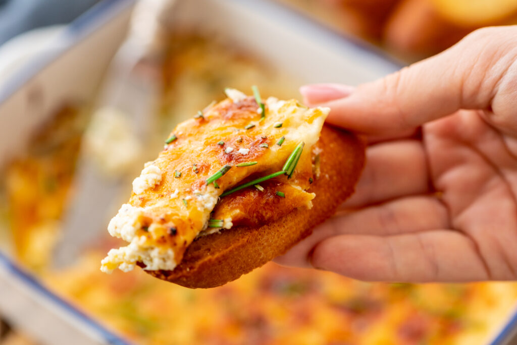 creamy baked ricotta cheese dip served on a toasted baguette bread slice.