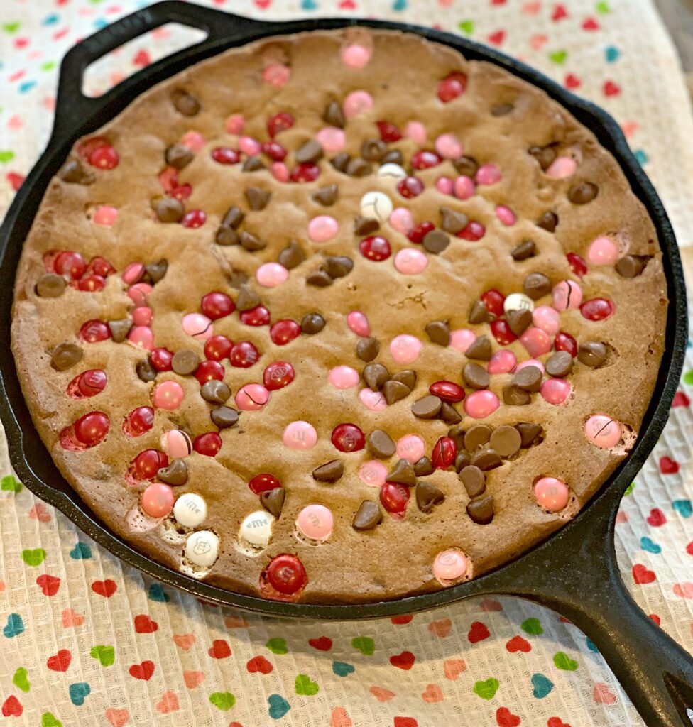 a valentines themed chocolate chip cookie baked in a cast iron skillet