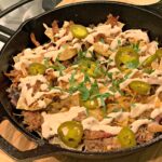 flavor packed loaded nachos with toppings, meat, and a sour cream sauce