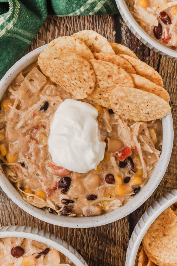 tortilla chips, sour cream, and cheese on top of chicken chili.