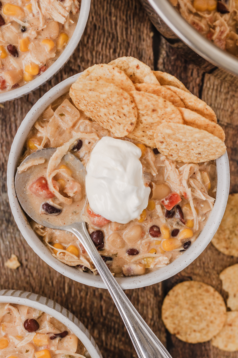 white chicken chili topped with sour cream, tortilla chips, and cheese in a soup bowl.