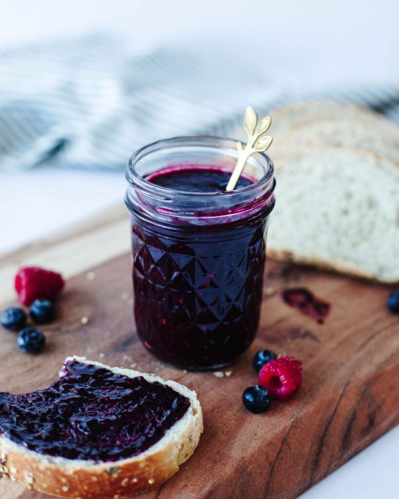 berry jam in a glass mason jar with toast.