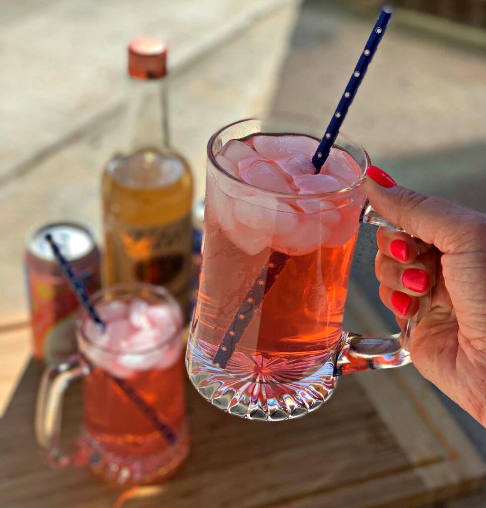 a barbie pink cocktail served in a cocktail glass with ice