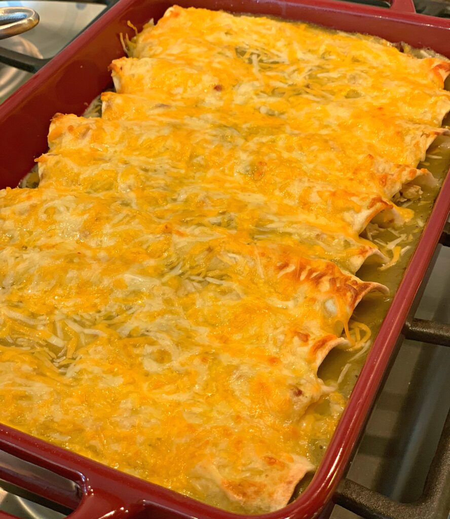 cheesy chicken enchiladas stacked in a baking pan