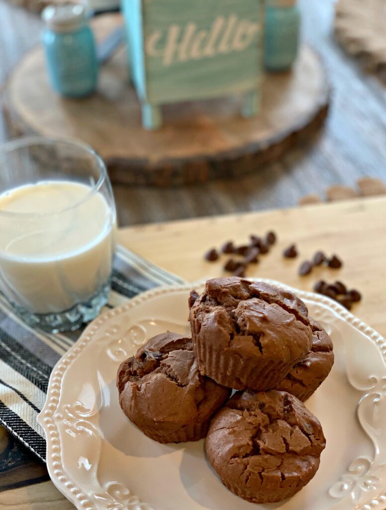 stacked chocolate peanut butter muffins next to a glass of white milk