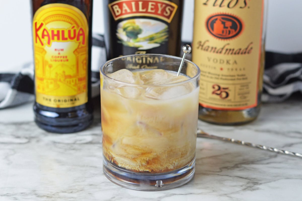 a creamy White Russian cocktail served with a stir stick.