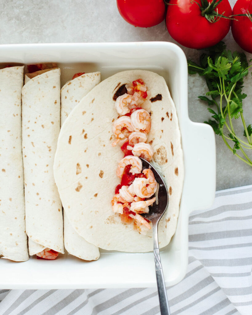 shrimp being rolled into a flour tortilla.