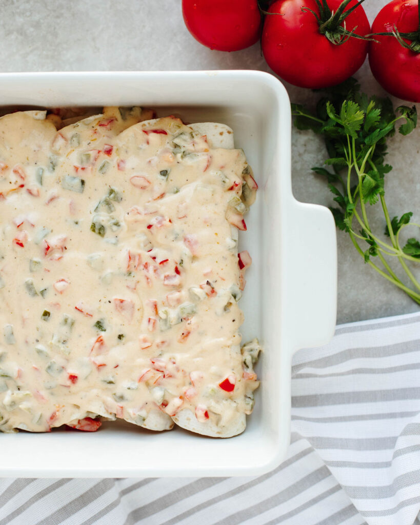 a homemade cream sauce over stuffed tortillas in a baking dish.