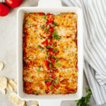 Creamy Shrimp Enchiladas topped with tomatoes in a white baking dish.