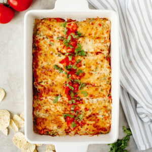 Creamy Shrimp Enchiladas topped with tomatoes in a white baking dish.