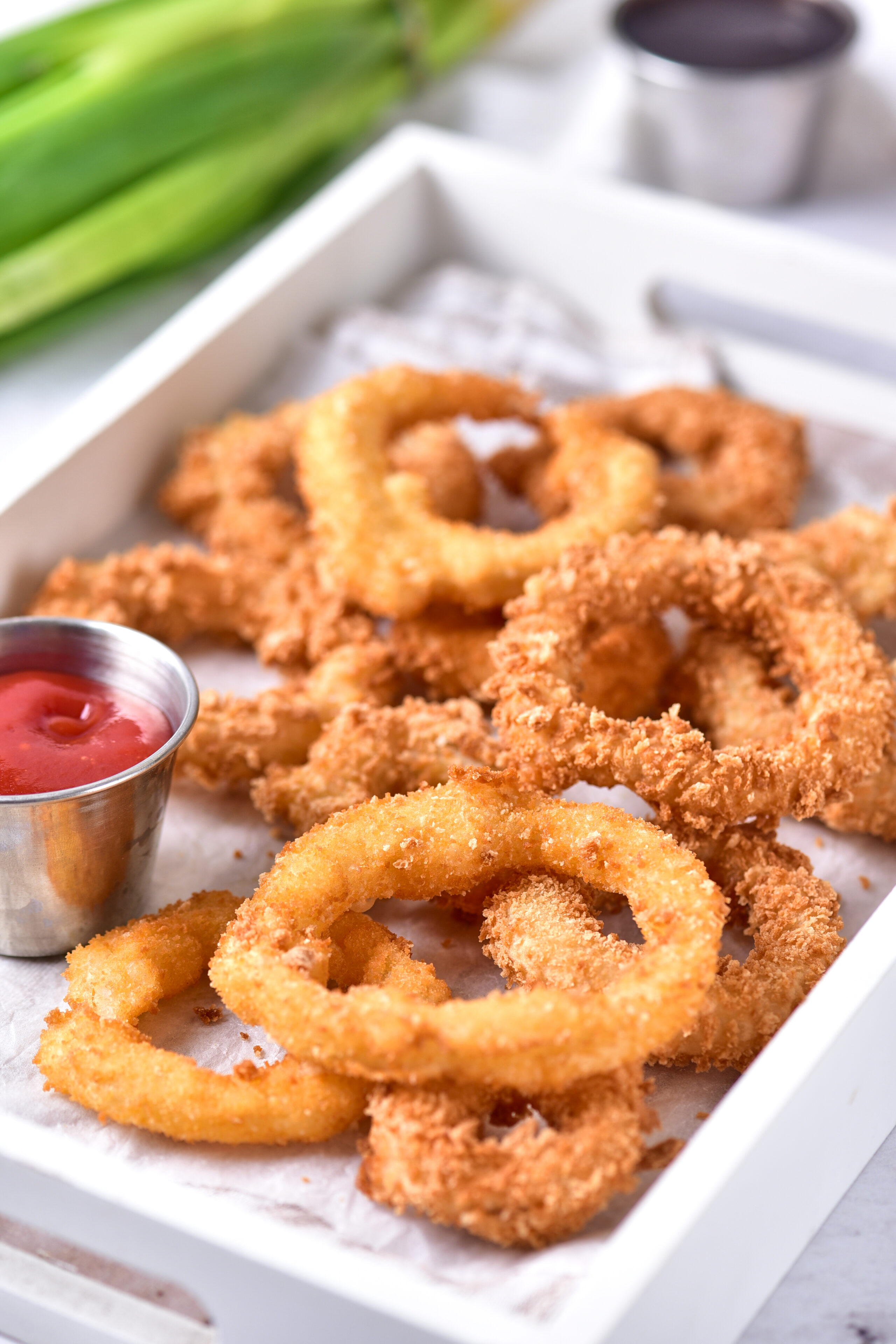 crispy onion rings in a basket with ketchup.