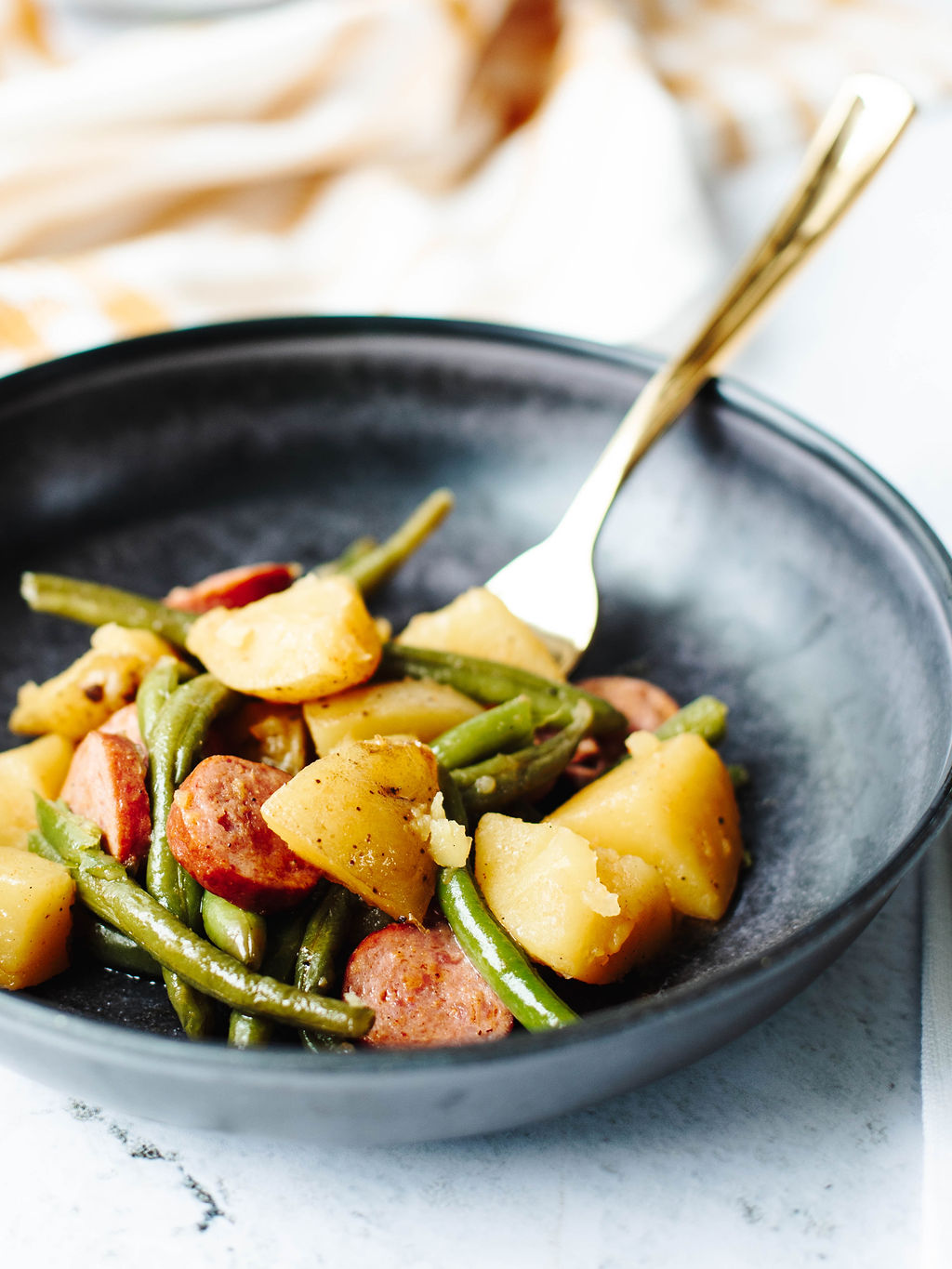 a serving of Cajun sausage, potatoes, and green beans on a dinner plate.