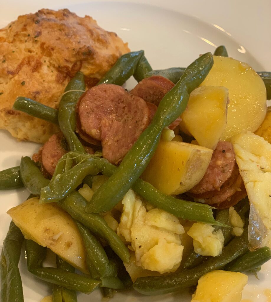 Delicious Instant Pot green beans, sausage, and potatoes served with a cheddar biscuit. 