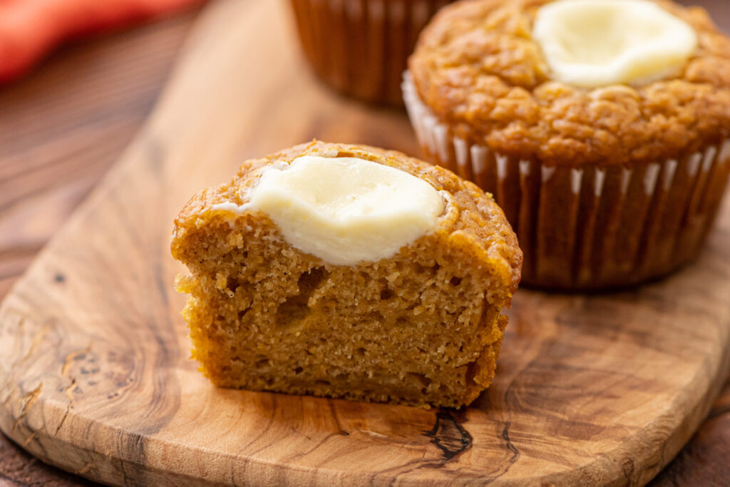 a pumpkin muffin sliced in half to show the cream cheese filling
