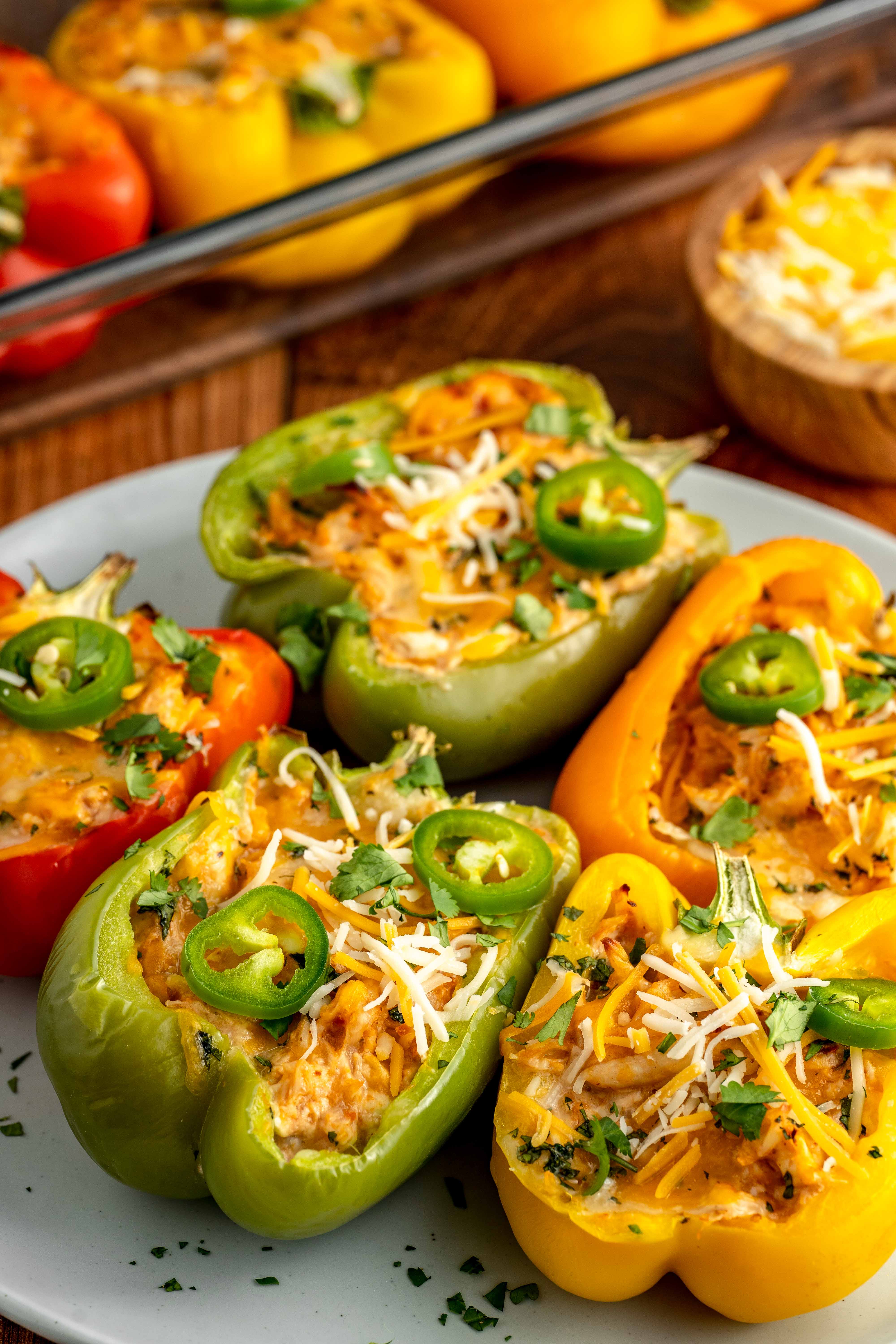 creamy chicken stuffed bell peppers on a white plate with cheese.