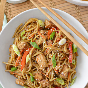 chicken lo mein served on a plate with chop sticks.