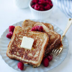 a white plate filled with french toast topped with raspberries.