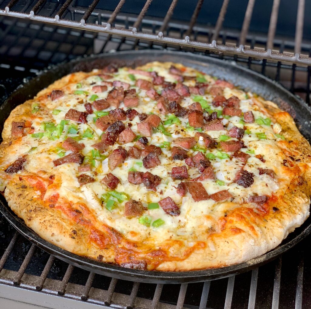 homemade pizza crust cooked on a smoker with lots of tasty toppings