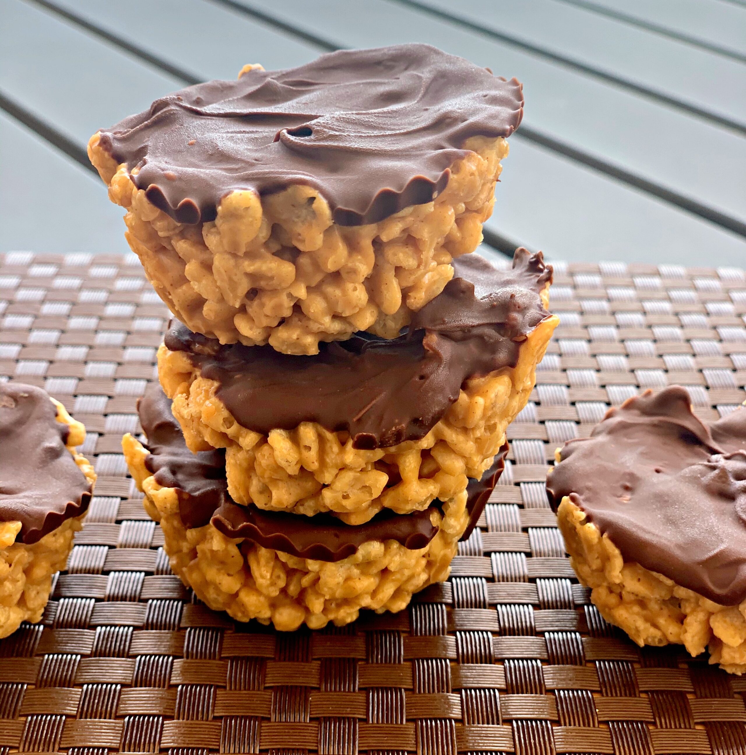 a stack of chocolate peanut butter rice krispy cups on a mat.