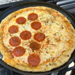 pizza cooked on a cast iron pan using simple ingredients