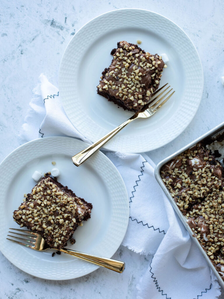 pieces of chocolate cake with a fudge frosting on white dessert plates.