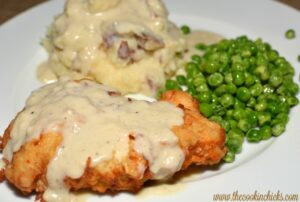 chicken fried chicken with mashed potatoes and green peas