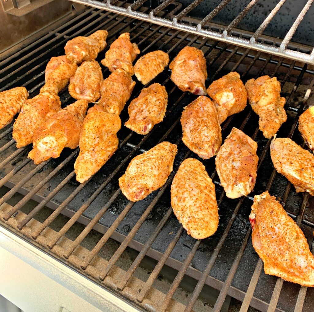 seasoned chicken wings lined up on the smoker