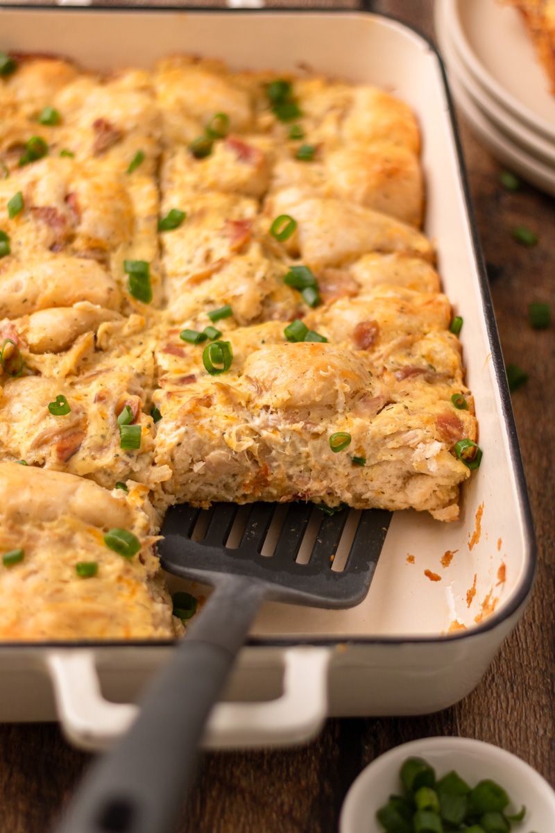 a slice of loaded chicken biscuit bake being removed from the casserole pan.
