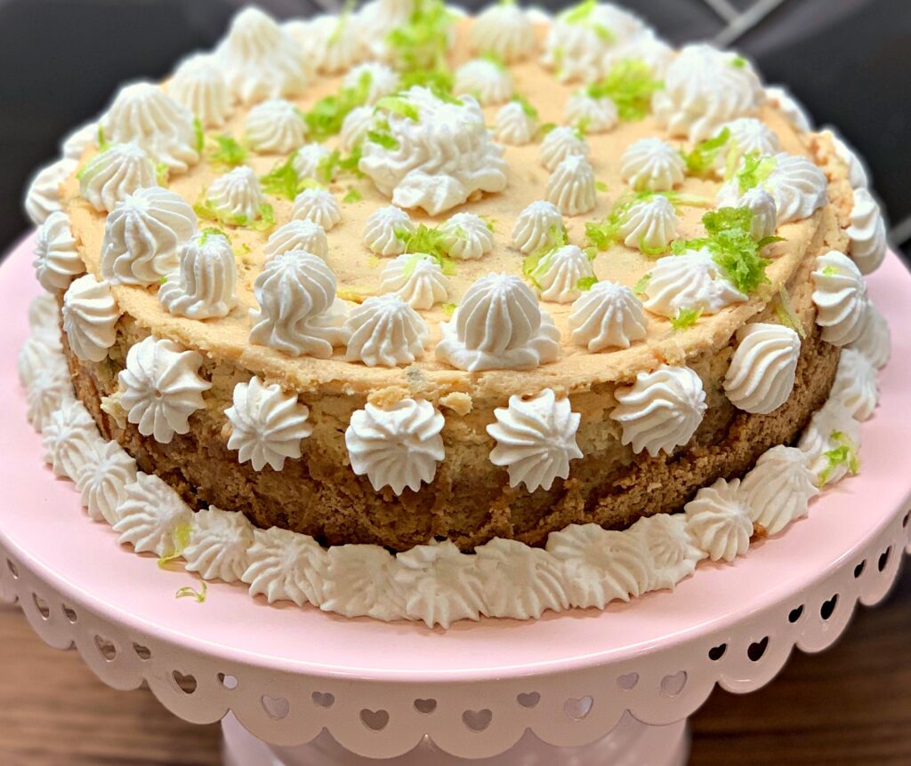 key lime cheesecake on a cake stand, topped with whipped cream
