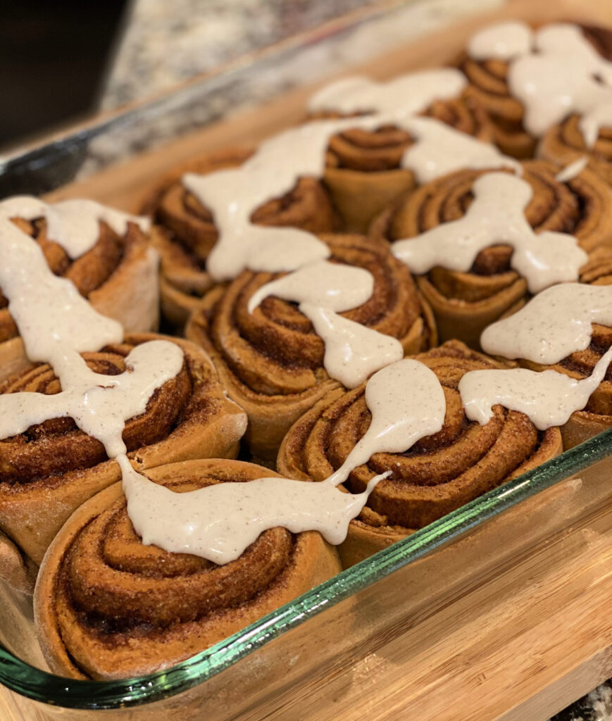 gingerbread frosting drizzled over fluffy, homemade cinnamon rolls
