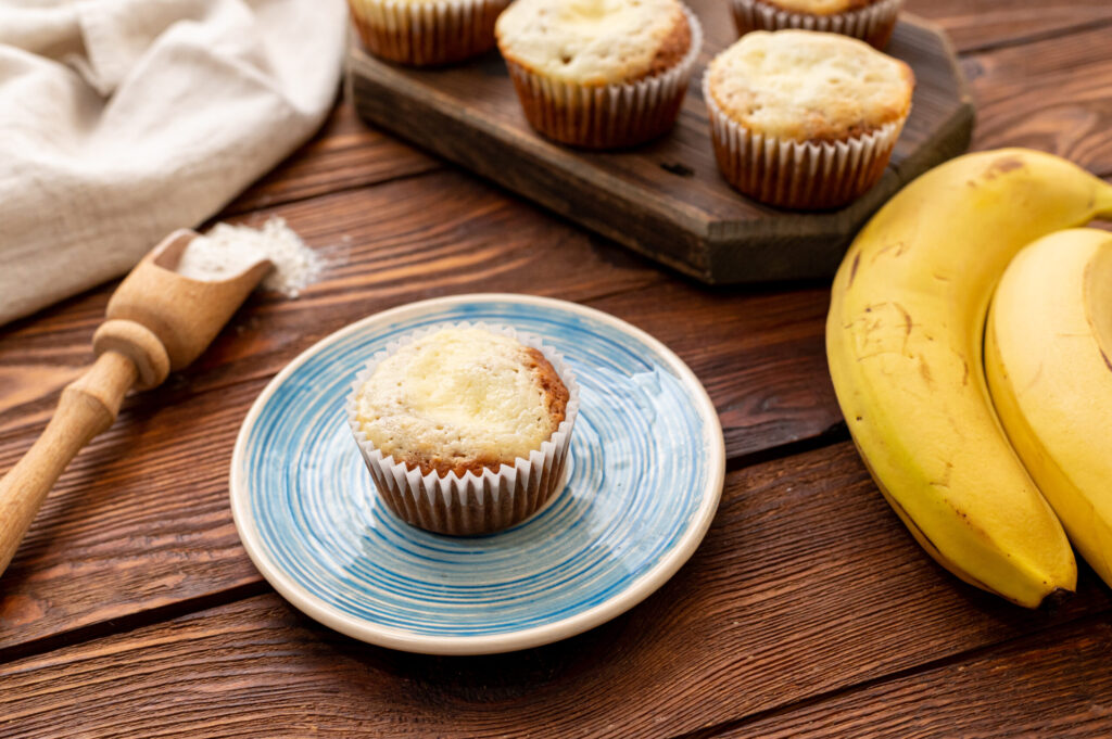 a banana muffin on a plate with a bunch of bananas next to it