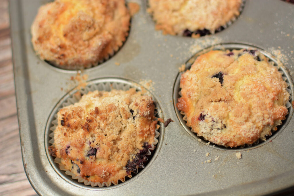 fluffy muffins with blueberries throughout and a crumb topping.