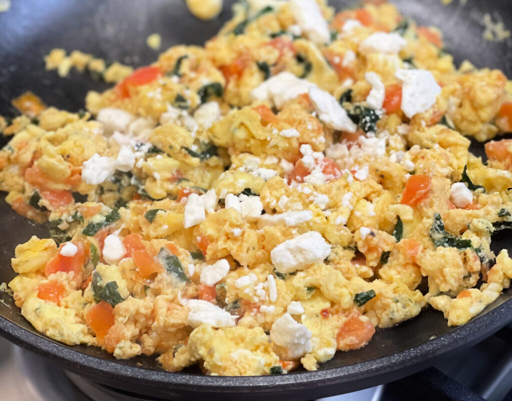 eggs combined with peppers, tomatoes, and feta to create a scramble