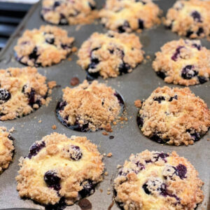crumb topped streusel blueberry muffins in a baking mufifn pan.
