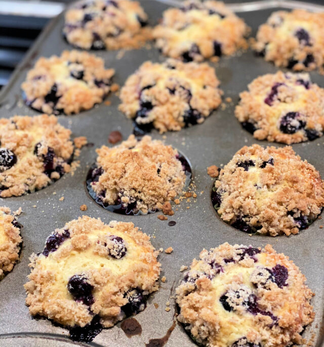 crumb topped streusel blueberry muffins in a baking mufifn pan.