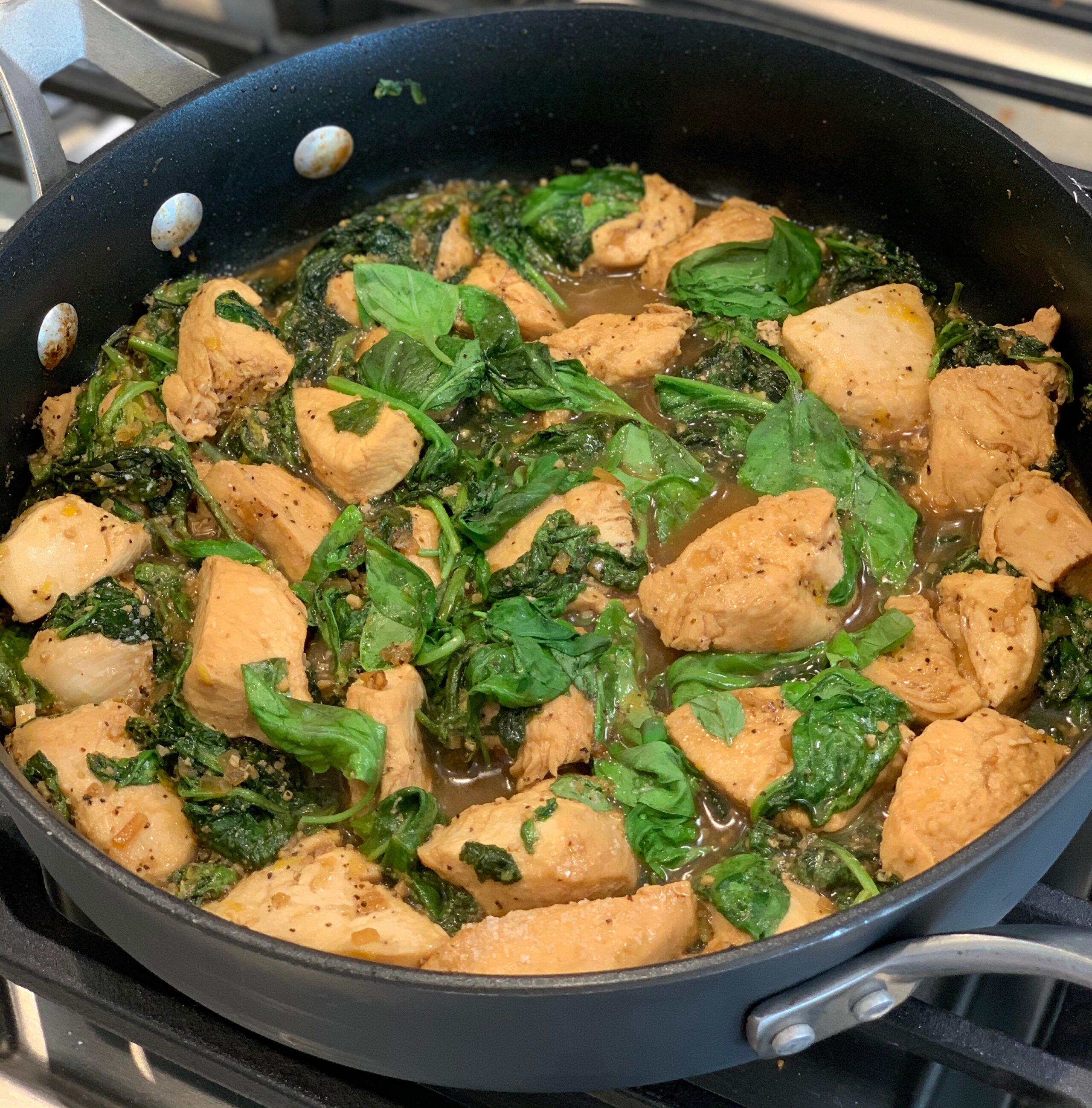 lemon basil chicken cooked in a skillet over the stove.