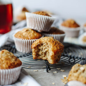 a bite taken out of a fluffy lightly sweetened muffin on a black wire rack.