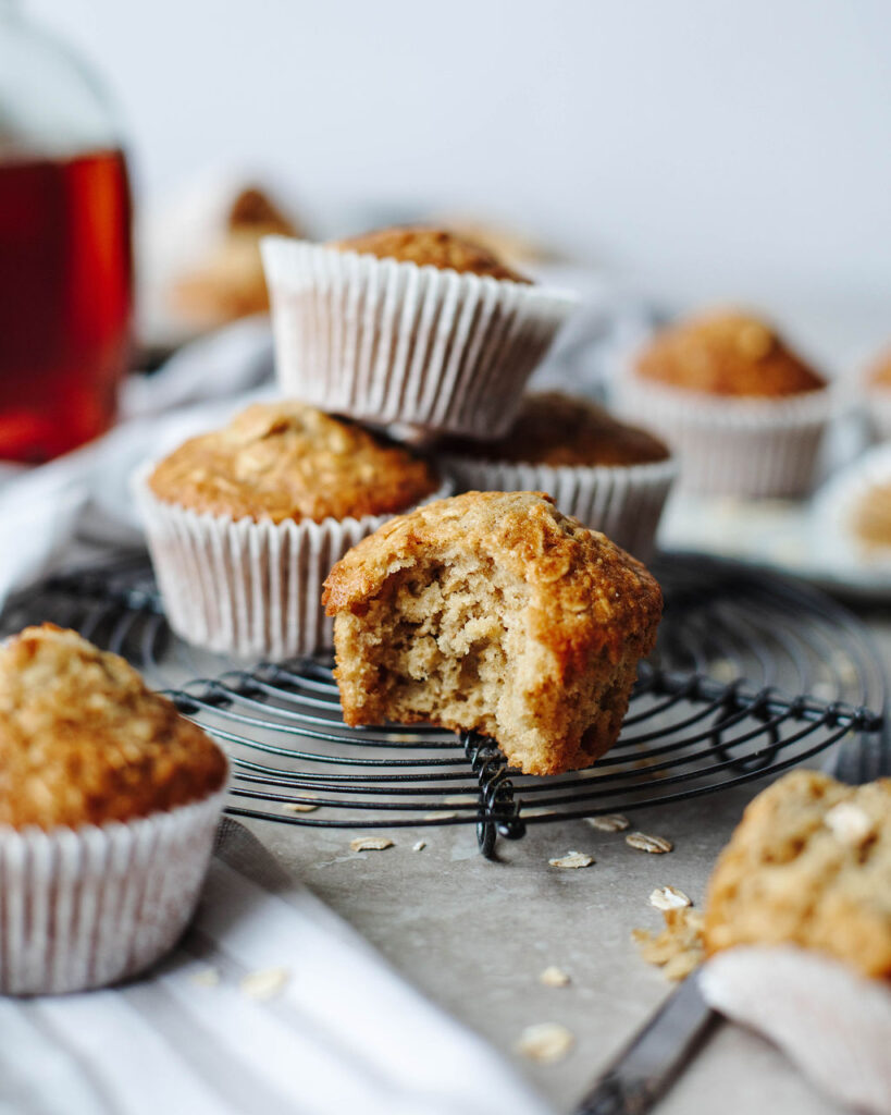 a bite taken out of a fluffy lightly sweetened muffin on a black wire rack.