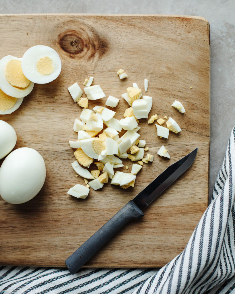 chopped hard boiled eggs on a wood cutting board.