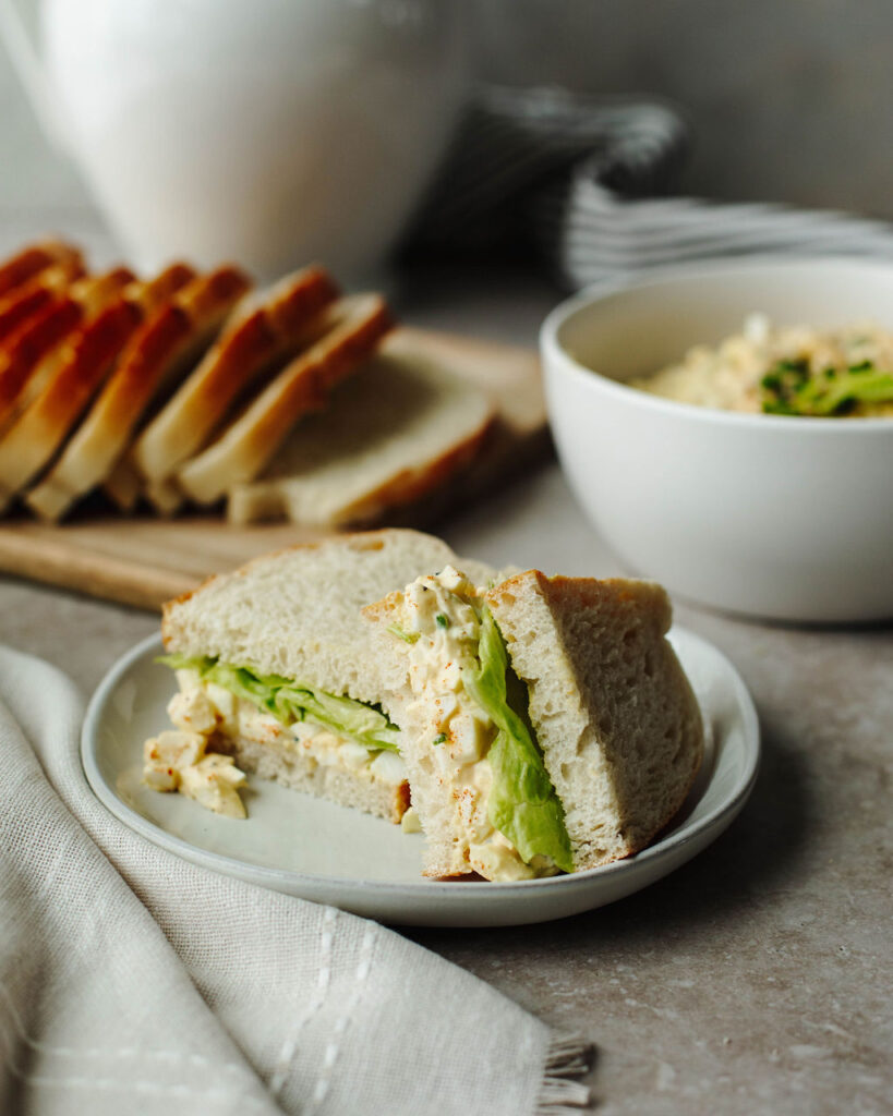 a sliced sandwich on a white plate with lettuce.
