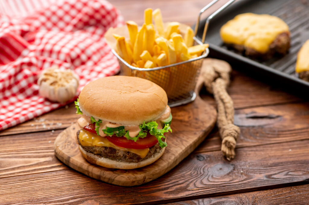 a juicy hamburger topped with cheese, lettuce, tomatoes, and sauce.