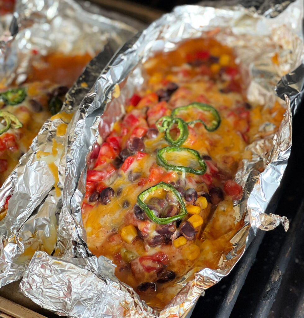 melted cheese, beans, corn, and tomatoes cooked over chicken in a foil packet on the grill