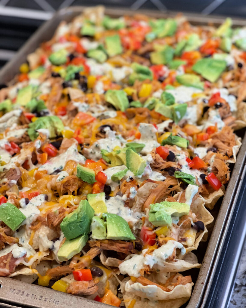 nachos loaded with pulled pork, peppers, avocado, beans, and more