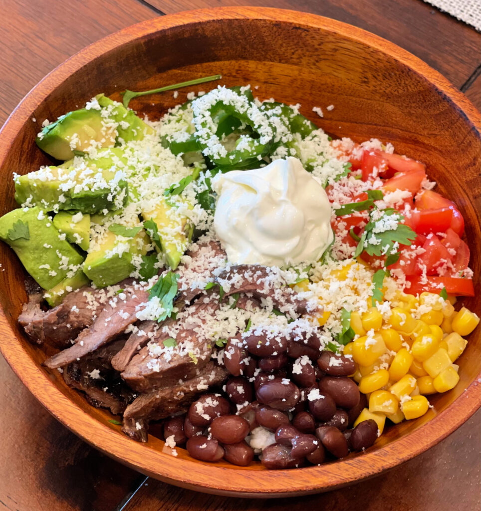 a sizzling steak burrito bowl with toppings loaded on top